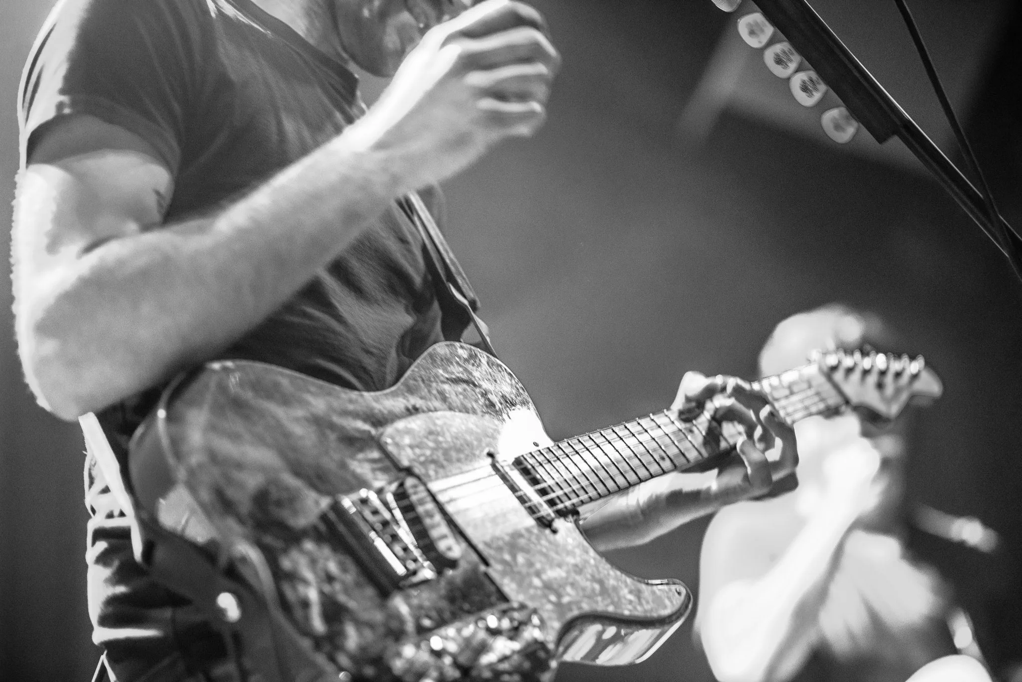 A guitarist mid-strum under stage light